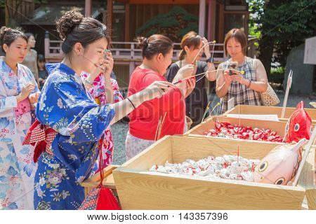 KAWAGOE JAPAN - 20 JULY 2016 - Japanese and Asian tourists try their luck by baiting lucky fortune paper fish form the piles at Hikawa Shrine in Kawagoe town Japan on July 20 2016.