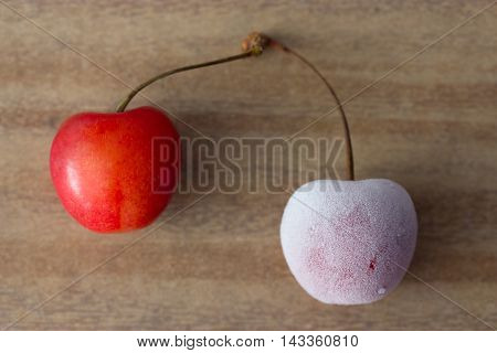 two cherries: one frozen and one fresh