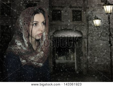 There is a face of a girl in a scarf on the background of night street.