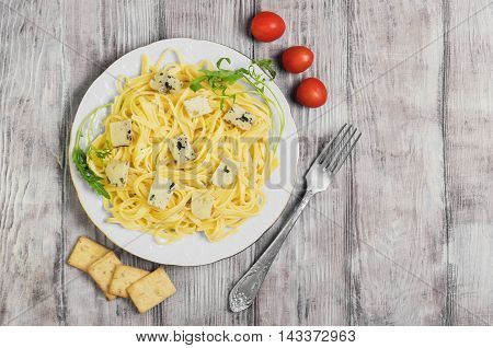 Spaghetti tagliolini with blue cheese cherry tomatoes lettuce crackers light white wooden background top view