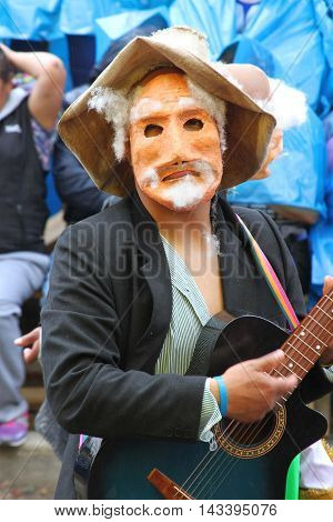 Cajamarca Peru - February 8 2016: Peruvian man with mask and sombrero plays guitar in Carnival parade in Cajamarca Peru on February 8 2016