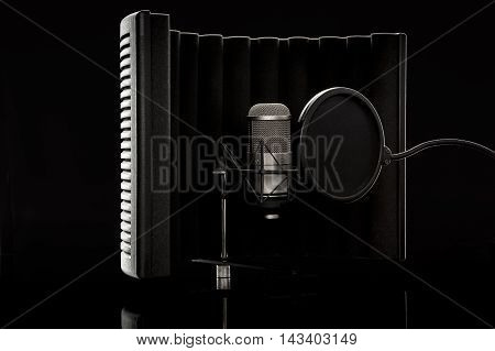 Studio microphone and shield against black background
