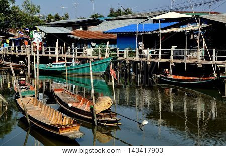Samut Songkhram Thailand - December 29 2011: Old wooden fishing boats docked in front of a cluster of Thai houses at a small fishing village nestled on the banks of an estuary