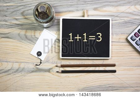sentence 1+1=3 written with chalkboard on a table with pen.Business, technology, internet concept.