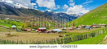 The old wooden fence and kitchen garden with old houses and Svan towers on the distance in Zhibiani village of Ushguli comunity Georgia.