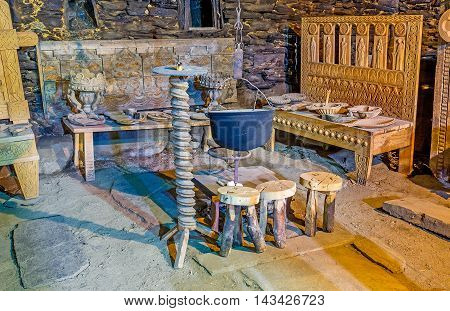 USHGULI GEORGIA - MAY 22 2016: The carved wooden benches and chairs stands around the cauldron for cooking over an open fire in Ethnographic Museum in the medieval house of Svan family on May 22 in Ushguli.