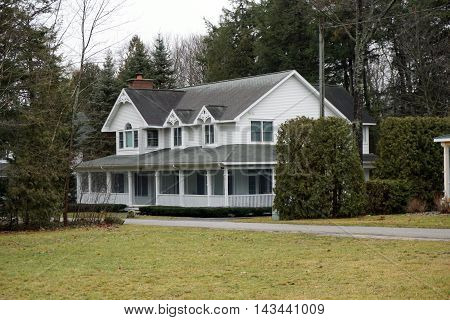 WEQUETONSING, MICHIGAN / UNITED STATES - DECEMBER 22, 2015: A large white home with a wraparound porch on Pennsylvania Avenue in Wequetonsing.