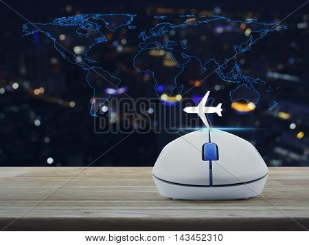 Wireless computer mouse with airplane icon on wooden table ovver world map and blur night city tower Airplane transportation concept Elements of this image furnished by NASA