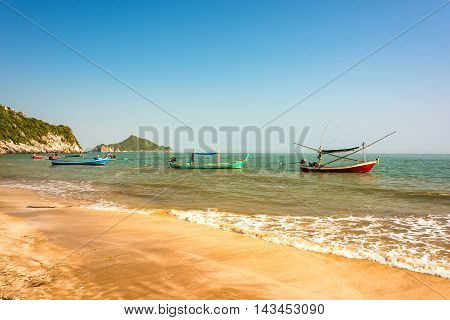 Tropical beach with sand shore and clear turquoise blue water and clear sky with colourfully decorated traditional Thai boats on shoal. Kui Buri Leam Sala Thailand