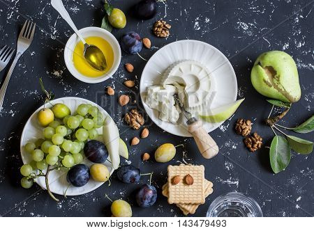 Snack table - goat cheese grapes pears plums nuts honey cracker. Top view