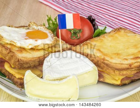 Plate with traditional french food - Close up over a plate with french white cheese salad tomato and the traditional croque sandwiches made with melted cheese ham and fried egg.