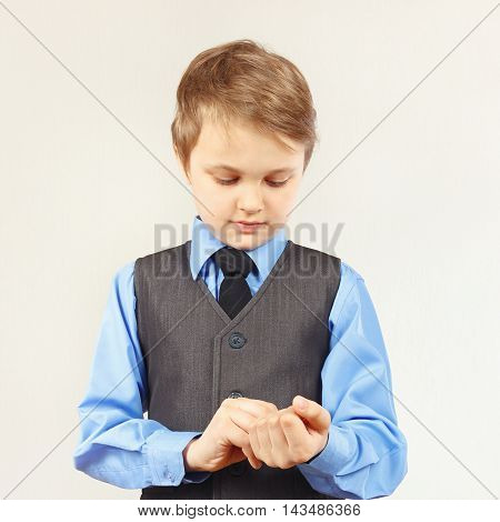 Little stylish boy fastened the buttons on sleeve his blue shirt