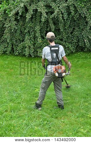 Verneuil sur Seine France - june 27 2016 :a woman is cutting lawn in a garden with a String trimmer