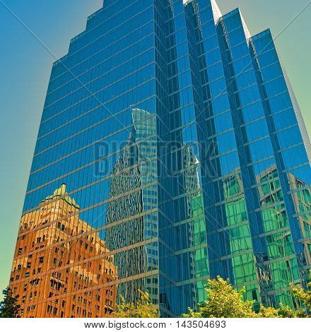 Reflecting city buildings in glasshaped skyscraper building blue sky