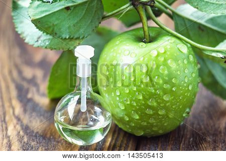 Apple vinegar in glass jar with ripe dreen fruit. Bottle of apple organic vinegar on wooden background. Healthy organic food.