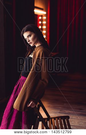 portrait of young brunette model woman posing in fashionable clothes in burlesque fitting room