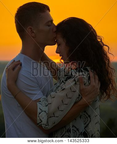 romantic couple at sunset on outdoor, beautiful landscape with bright yellow sky, love tenderness concept, young adult people