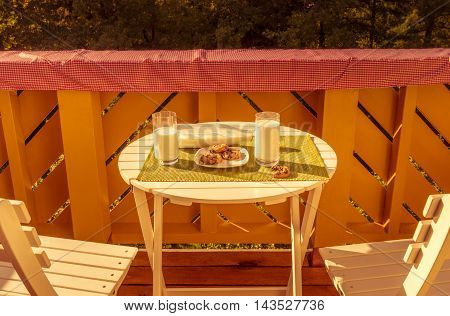Cookies with milk on round table
Joyful food photography with a breakfast, cookies and glasses of milk, served on a balcony on a small white table.