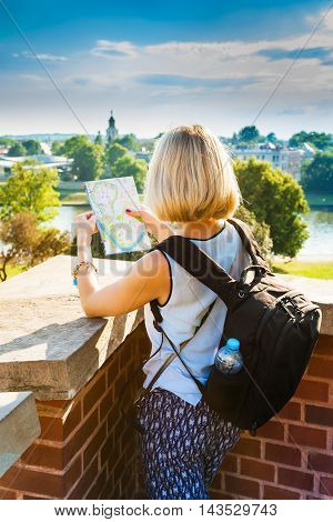 Female traveler stands and looking at map of the city on the background of modern residential quarter of Krakow and Vistula River. Wawel castle. Poland.