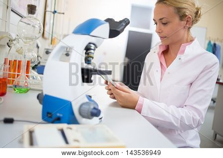 Female lab worker look for chemical data at ipod in laboratory