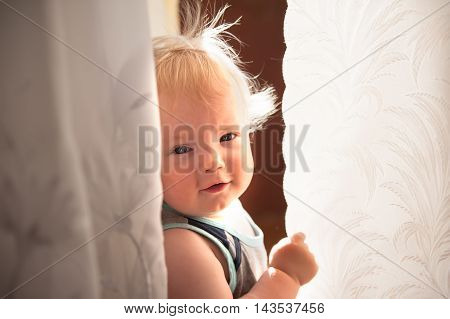 A cute little baby is looking into the camera and is wearing a white hat. The baby could be a boy or girl and has blue eyes. use it for a parenting or love concept.