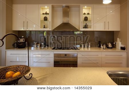 Modern kitchen, with granite benchtops and reflective glass splashback.