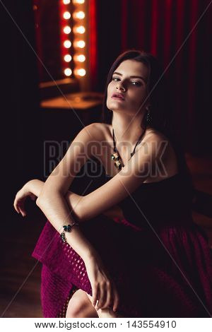 indoor shot of young brunette model posing in fashionable clothes in burlesque fitting room