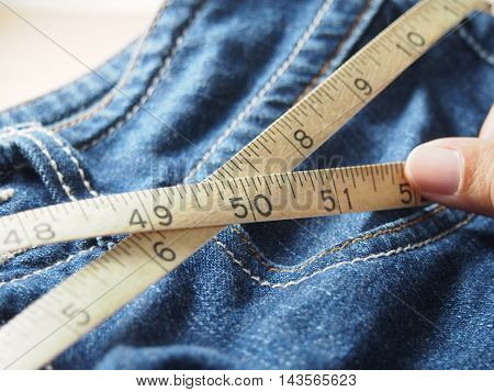 Holding tapeline on waist of blue jeans