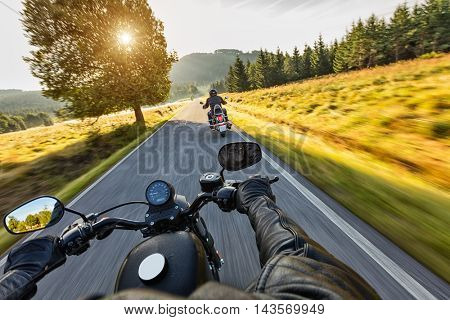 Motorcycle drivers riding on motorway in beautiful sunset light. Shot from pillion driver view