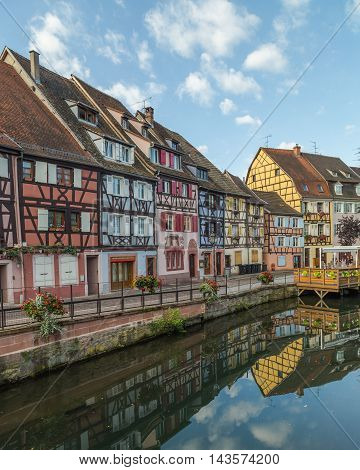 COLMAR FRANCE - 30TH JULY 2016: A view of colourful timber framed buildings along Little Venice in Colmar during the morning. Reflections can be seen in the River Lauch