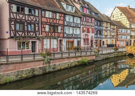 COLMAR FRANCE - 30TH JULY 2016: A view of colourful timber framed buildings along Little Venice in Colmar during the morning. Reflections can be seen in the River Lauch