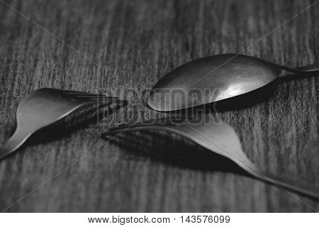 Cutlery set - two forks and a spoon on a wooden table. Monochrome photo