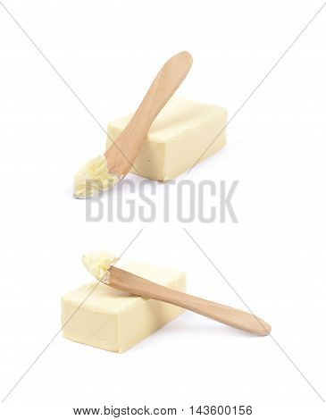 Wooden knife over a briquette piece of a butter, composition isolated over the white background, set of two different foreshortenings