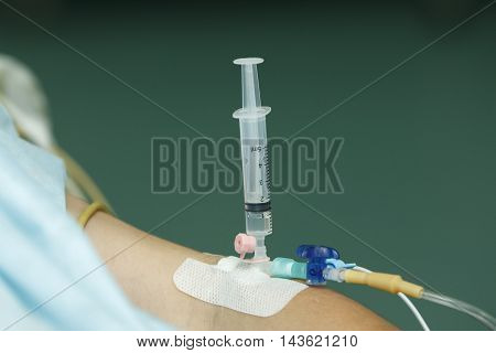 5 ml syringe with a drug inserted into catheter in patients hand close-up