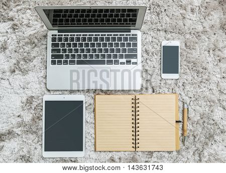 Closeup brown note book with line in page brown pen computer notebook tablet and smart phone on gray fabric capet textured background in top view in work concept