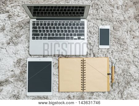 Closeup brown note book with blank space in page brown pen tablet and smart phone on gray fabric capet textured background in top view in work concept