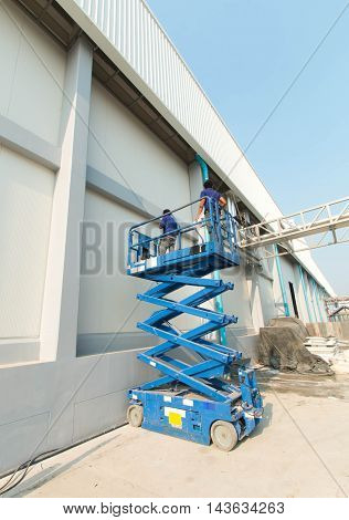 Builder on a Scissor Lift Platform at a construction site. Men at work