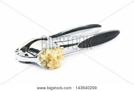 Used metal garlic press utensil with a crushed clove, composition isolated over the white background