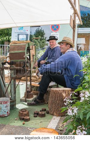 Men Sitting Next To An Ancient Machine To Thresh Grain