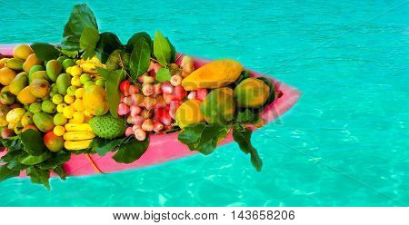 The exotic tropical fruits on the boat canoe against blue water