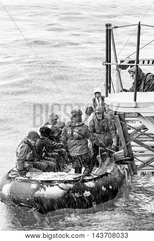 SOUTH GEORGIA, GREAT BRITAIN - NOV 9, 2012: Unidentified group of people in a water proof suit in a rubber boat with a motor in the Atlantic Ocean. Atlantic Ocean is the world's second largest ocean