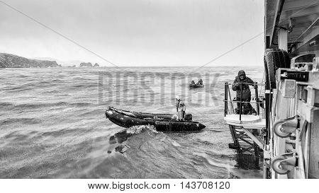 SOUTH GEORGIA, GREAT BRITAIN - NOV 9, 2012: Unidentified man goes down to get a place in a boat in the Atlantic Ocean. Atlantic Ocean is the world's second largest ocean