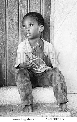 KARA, TOGO - MAR 9, 2013: Unidentified Togolese boy sits at the porch of a house. Children in Togo suffer of poverty due to the unstable econimic situation