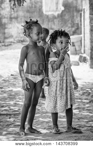 KARA, TOGO - MAR 9, 2013: Unidentified Togolese girls walk in the street. Children in Togo suffer of poverty due to the unstable econimic situation