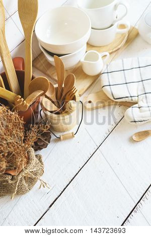 Kitchen cooking utensils on a shelf with white rustic wooden background