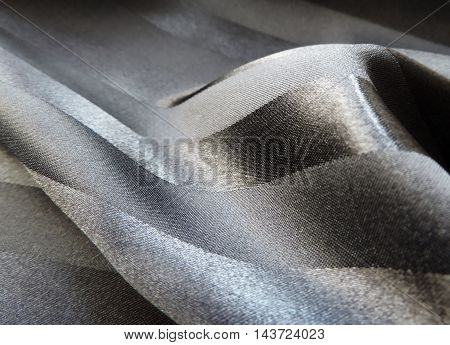 Wavy, black satin cloth or textile with strips, textile background with copy space.