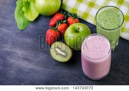 Strawberry and spinash smoothies in glasses with ingredients on dark background selective focus.