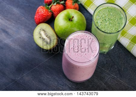 Strawberry and spinash smoothies in glasses with ingredients on dark background selective focus.