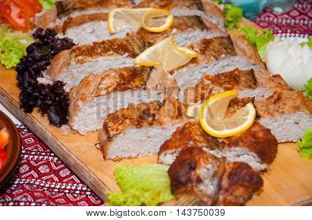 Meat pie on a wooden board decorated with lemon and herbs