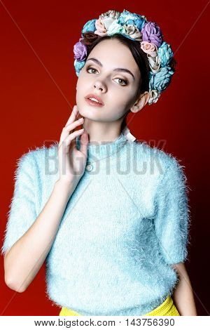 Beautiful model with a wreath of flowers on her head on red background